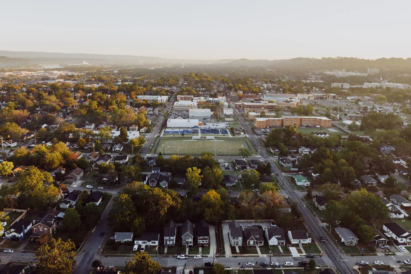 Aerial view of tree-lined neighborhoods and a town center at golden hour