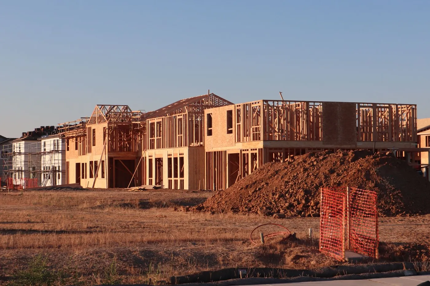 The timber frames of new two-story homes going up in a residential subdivision at sunset